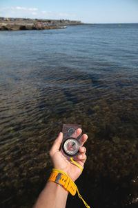 Midsection of person holding sea against sky