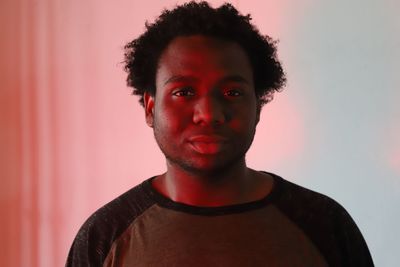 Close-up portrait of young man standing against wall