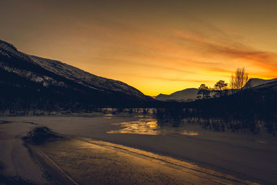 Scenic view of frozen lake against sky during sunset