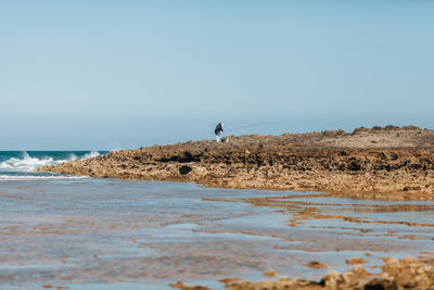 Man on beach against clear sky