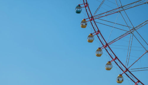 Low angle view of ferris wheel against clear blue sky