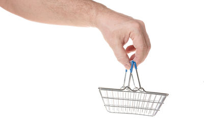 Close-up of hand holding basket over white background