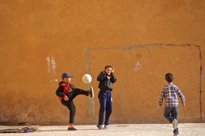 Rear view of people standing against wall