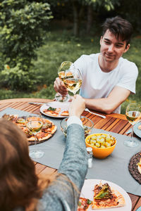 Friends making toast during summer picnic outdoor dinner in a home garden