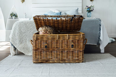 Boy hiding in wicker basket at home