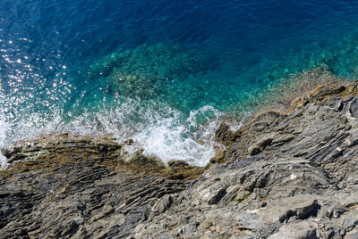 Top view of a turquoise sea and black granite cliff