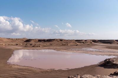 Gathered water in a arid lake in dasht e lut or sahara desert with cloudy sky