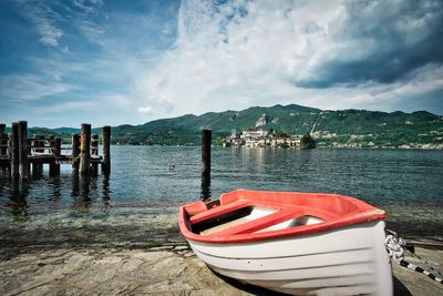 Boat moored on lake against sky