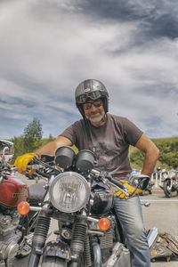 Portrait of man riding motorcycle against sky