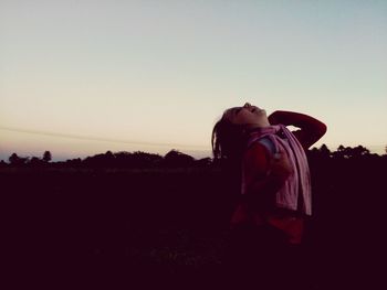 Woman standing on field against clear sky during sunset