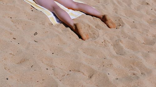 Low section of woman lying on sand