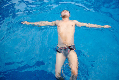 High angle view of shirtless man floating on water