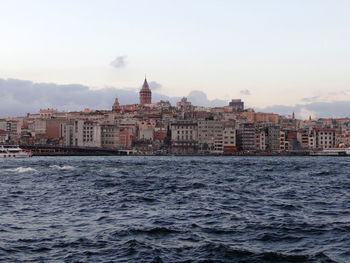 Scenic view of town next to sea against cloudy sky