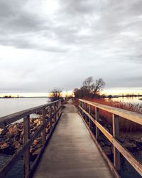 Footbridge over sea against sky