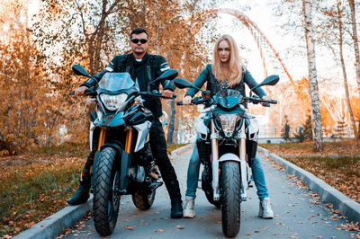 Couple sitting on motorcycles during autumn