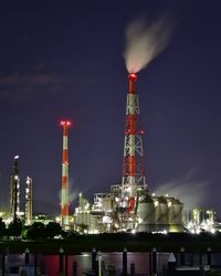 Illuminated factory against sky at night