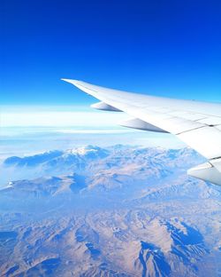 Aerial view of snowcapped mountain against blue sky