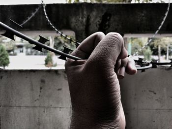 Cropped hand of man holding wire