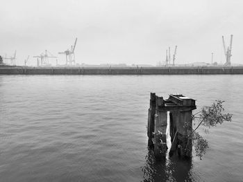 View of wooden post in sea against sky