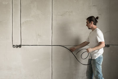 Side view of man standing against wall