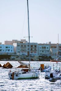 Boats moored on lake against buildings and clear sky