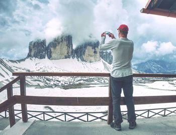 Hiker takes phone photo in mountains. man on alps mountain peak. mountains increased from humidity