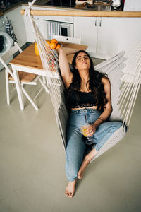 Young woman relaxing on hammock at home