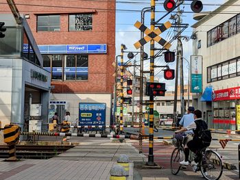 People riding bicycle on street against buildings in city