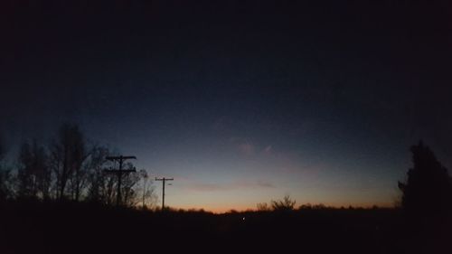 Silhouette of trees on landscape at sunset