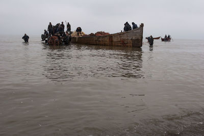 Fishermen fishing in sea against clear sky