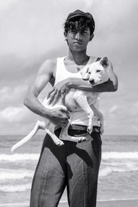 Portrait of mature man standing at beach against sky