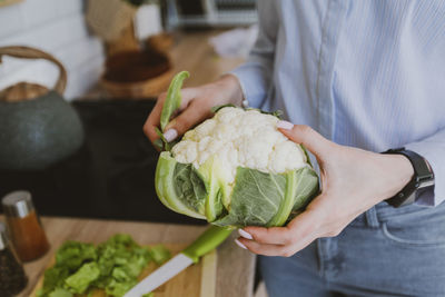 Closeup of female hands holding big white cauliflower, fresh raw vegetables,