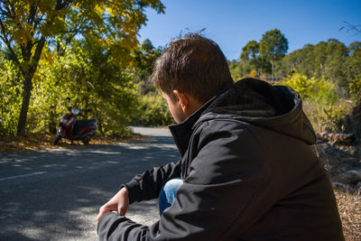 Rear view of man sitting on road