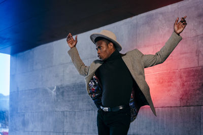 Full length of man wearing hat standing against wall