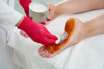 Hand of beautician applying cream on woman's feet