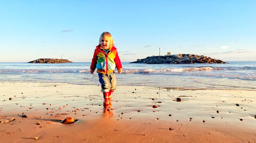 Full length of boy standing on beach against sky