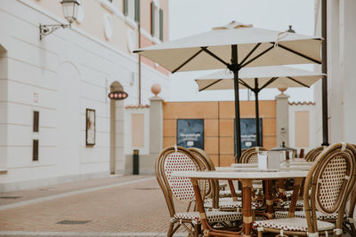 Empty chairs and tables against building