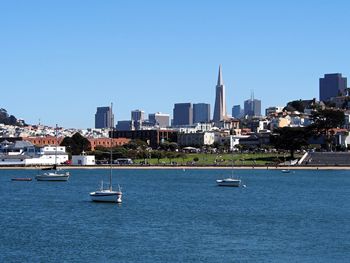 Boats in river with city in background