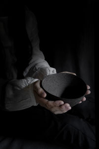 Midsection of woman holding bowl in darkroom