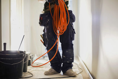 Low section of male carpenter holding wire cables at site