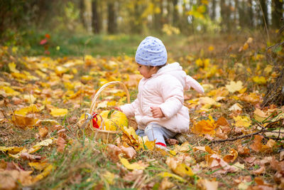 Full length of girl sitting on field during autumn