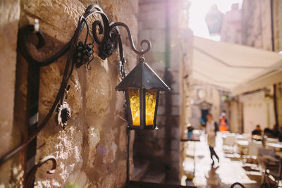 Close-up of lamp hanging on wall of building