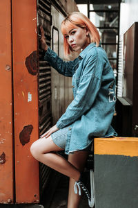 Side view of young woman standing against door