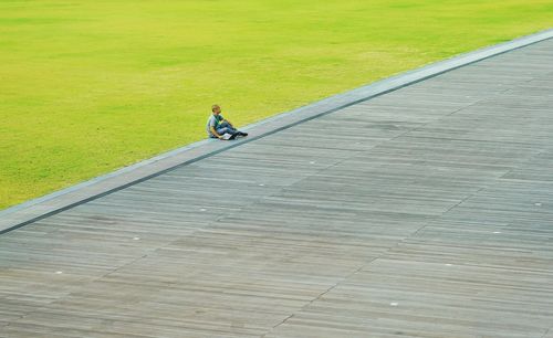 High angle view of man sitting on footpath