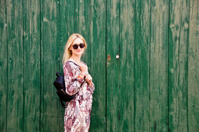 Portrait of beautiful woman standing against wooden wall