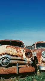 Abandoned cars against blue sky