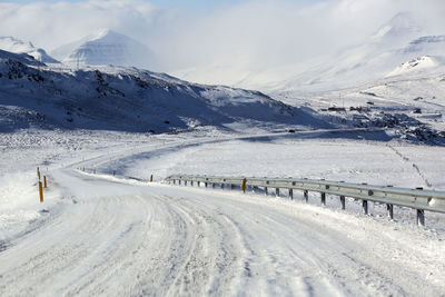 Snowy road with volcanic mountains in wintertime, iceland