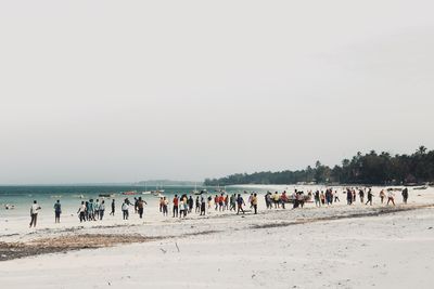 People on beach against clear sky