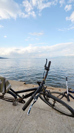 Bicycle by sea against sky