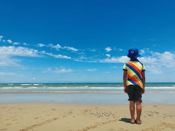 Woman standing on beach against blue sky